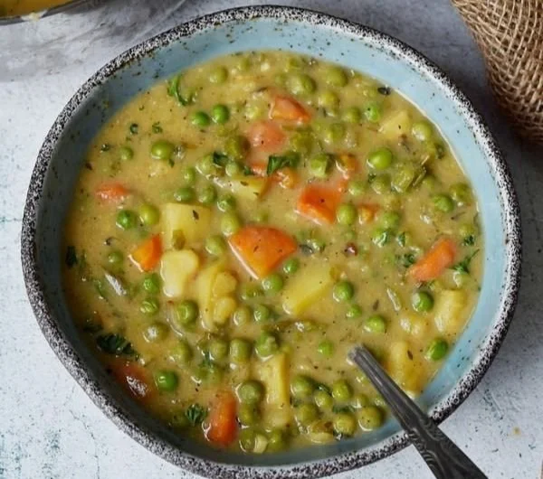 Schüssel mit veganer Gemüsesuppe, reich an frischem Gemüse und Kräutern.
